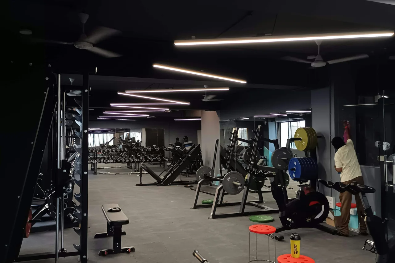 Weight benches and training equipment beneath angled lights in a gym.